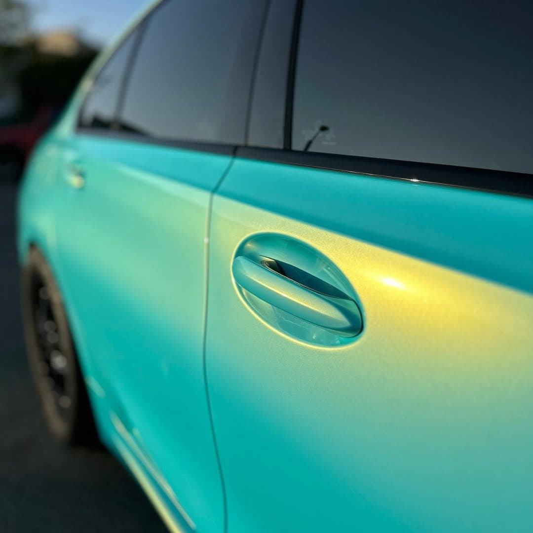 Closeup of teal-to-gold color-flip vinyl on a sedan door